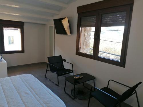 Villar de CanesCASA RURAL MENSIN的一间卧室配有两把椅子、一张床和两个窗户。