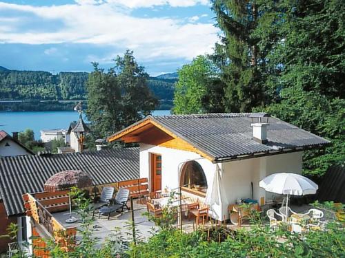 沃尔特湖畔韦尔登Ferienwohnung Schellander Privatstrand的一座小房子,设有配有椅子和遮阳伞的庭院