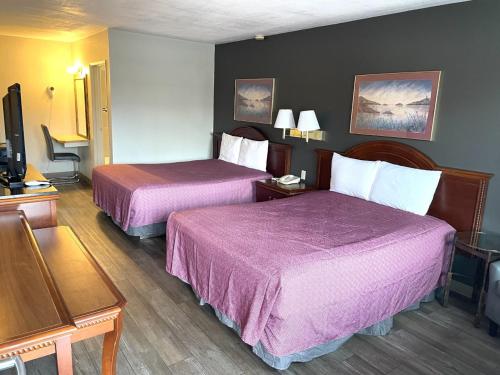 韦纳奇Downtown Inn的酒店客房,配有两张带紫色床单的床