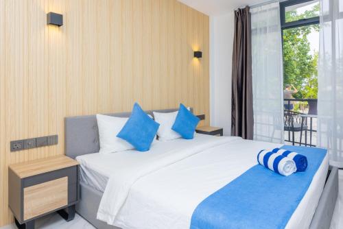 丹格迪Atoll Residence Dhangethi的卧室配有带蓝色枕头的大型白色床