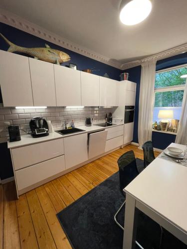 基尔Luxus Altbaucharme in zentraler Lage的厨房配有白色橱柜和蓝色的墙壁