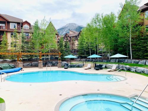 坎莫尔Stoneridge Mountain Resort Condo hosted by Fenwick Vacation Rentals的庭院内的游泳池,配有椅子和遮阳伞