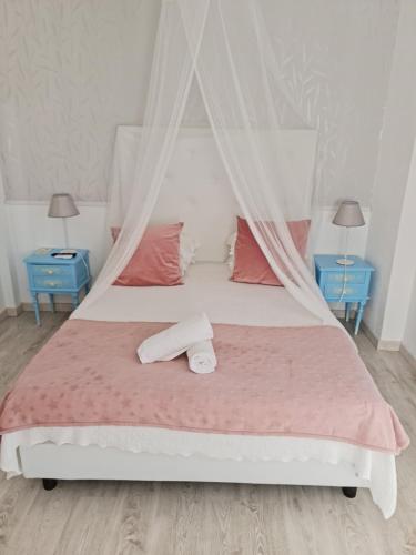 米尔芳提斯城Casa da Alagoinha的一间卧室配有一张带粉红色床单和两张蓝色桌子的床。