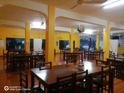HomúnHotel Santa María Homun的餐厅设有木桌和椅子,墙壁为黄色