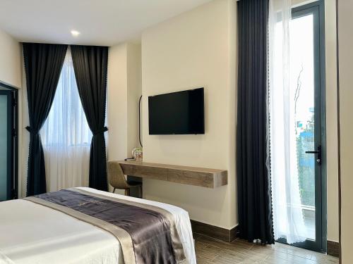芹苴LION 5 HOTEL的酒店客房配有一张床、一张书桌和一台电视。