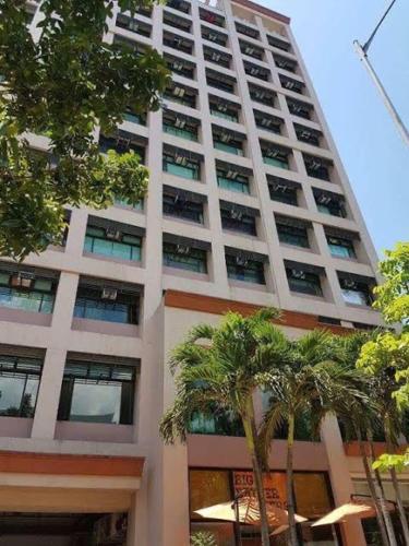 马尼拉Alabang Condotel的一座高大的建筑,前面有棕榈树