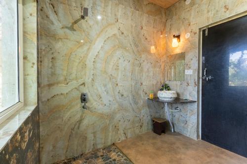 坎哈Jungle King Resort的浴室设有带淋浴的石墙
