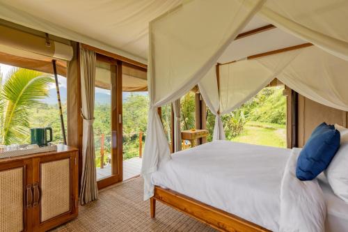 塔巴南Nadi Nature Resort - Adults Only的一间卧室设有一张天蓬床和一个阳台