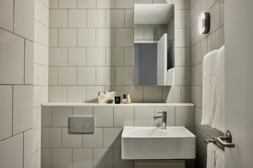 悉尼Punthill Parramatta的白色瓷砖浴室设有水槽和镜子