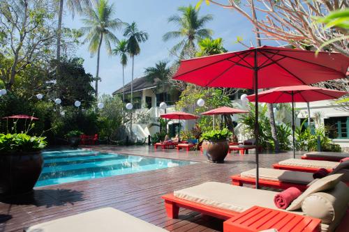 琅勃拉邦玛丽别墅精品酒店的毗邻度假酒店的带椅子和遮阳伞的游泳池