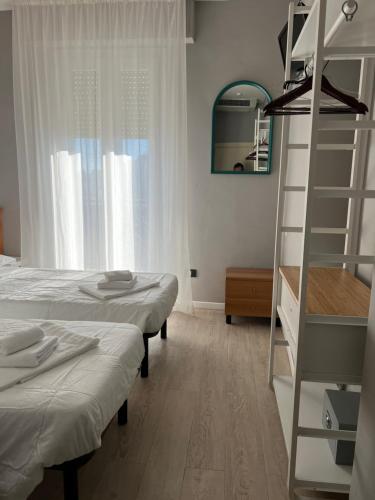 里米尼斯特拉意大利亚酒店的一间卧室设有两张床、梯子和镜子