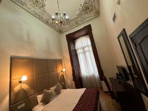 巴库Gardenian Hotel Baku的一间卧室配有一张床、一个吊灯和一扇窗户