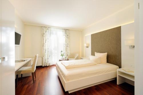 劳茵戈恩卡奈凯勒酒店的卧室配有白色的床、书桌和窗户。