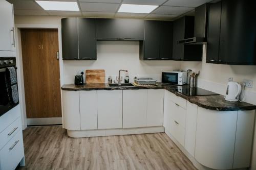 DaliburghUist Travel Accommodation的厨房配有白色橱柜和黑色家电