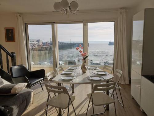 格朗维尔Charme et zénitude, avec vue exceptionnelle sur le port的客厅配有桌椅和大窗户