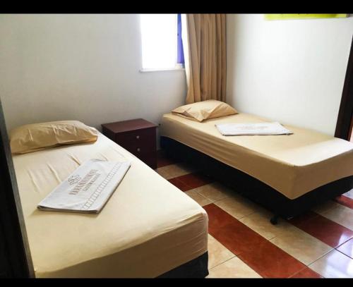 曼加拉蒂巴Itacuruça Palace Hotel的酒店客房设有两张床和窗户。