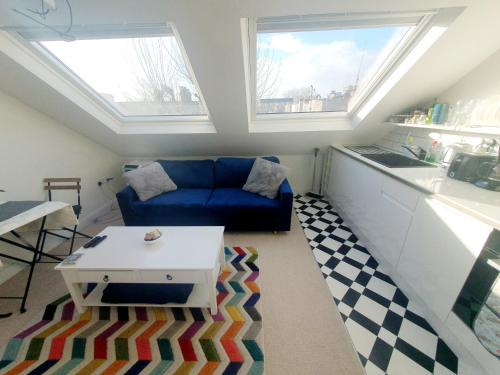 伦敦Jacuzzi Suite的客厅设有蓝色的沙发和2扇窗户。