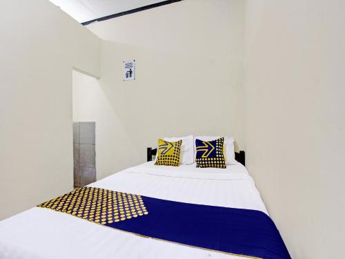 GlagahSPOT ON 92220 Sari Laut的白色的客房配有黄色和蓝色枕头的床