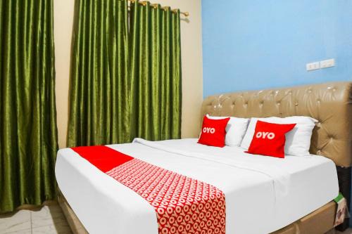 SunggalSUPER OYO 92075 Sky Residence Mawar的一间卧室配有一张带红色枕头和绿色窗帘的床