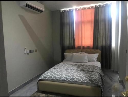 SpintexAdonai Luxury Apartments Accra的一间卧室配有床和带窗帘的窗户