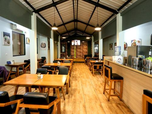 雅加达Super OYO Townhouse OAK Hotel Fiducia Pondok Gede的一间带木桌椅的餐厅和一间酒吧