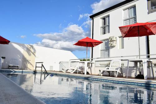 科隆Catalina Hotel的一座带椅子和遮阳伞的游泳池位于一座建筑旁边