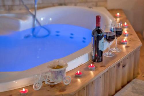 Reẖovסוויטות פנינת המעיינות的浴缸配有一瓶葡萄酒和酒杯