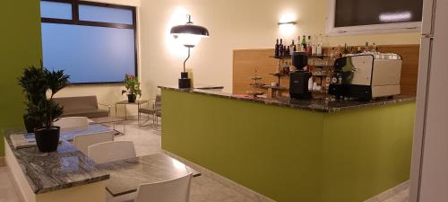文蒂米利亚Hotel Posta的餐厅设有绿色的酒吧,配有白色的椅子