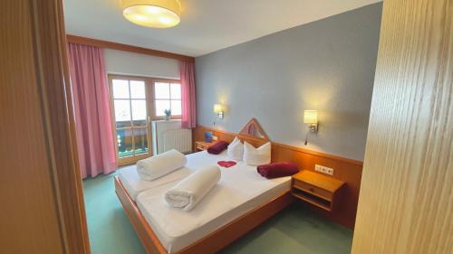 曼达芬Pension Alpin的卧室配有带白色枕头的床和窗户。