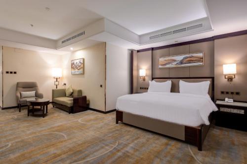 吉达Al Ertiqaa Hotel的酒店客房带一张大床和一把椅子