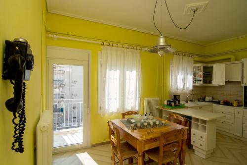 沃洛斯Areti' s Home的厨房设有黄色的墙壁和桌椅