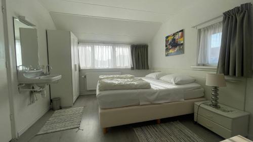 海边的艾格蒙特Strandhuis Everts的白色卧室设有床铺和水槽