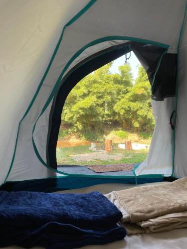 瑟格莱什布尔Byrahalli Bliss riverside camping的帐篷的门打开,里面设有一张床