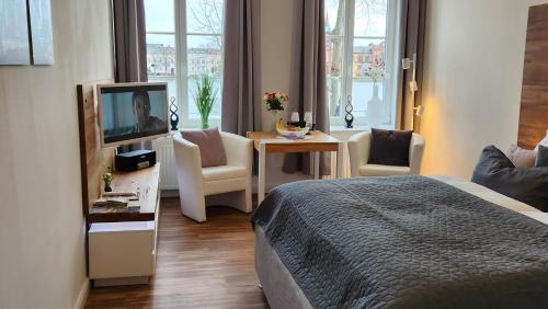 什未林Das Ferienapartment Alexandrine direkt am Pfaffenteich mit eigenem Parkplatz的一间酒店客房,配有一张床、一台电视和一张桌子