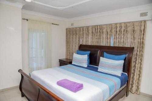 卢萨卡Royal Suites Apartments的一间卧室配有一张大床,上面有一条紫色毛巾
