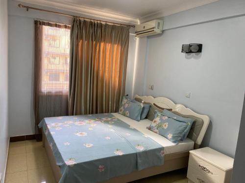 达累斯萨拉姆Masaki Anne H & Apartment的一间卧室配有一张带蓝色床单的床和一扇窗户。
