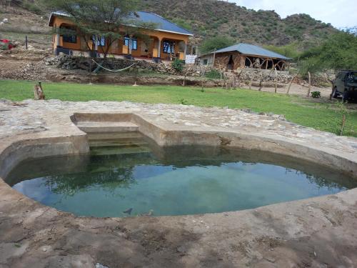 MtowabagaLake Natron Maasai Guesthouse的房屋前方的大水池