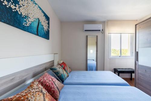 塞维利亚Miraflores Luxury Suites的一间卧室配有一张带蓝色床单的床和墙上的绘画。