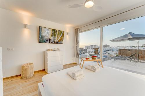 帕莱索海滩Calma Paraiso的卧室设有白色的床和大窗户