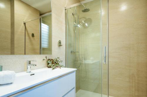 塞维利亚Apartmentos Marqués de Nervion的一间带玻璃淋浴和水槽的浴室