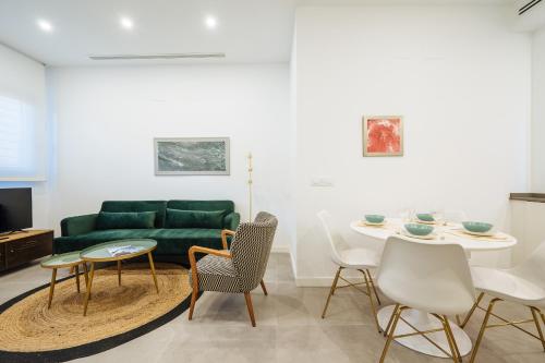 塞维利亚Apartmentos Marqués de Nervion的客厅配有绿色沙发、桌子和椅子