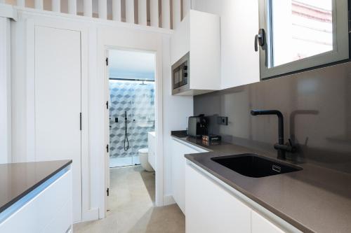 塞维利亚apartamentos montevideo 6的厨房配有白色橱柜和水槽