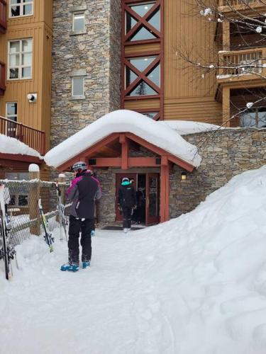 潘诺拉马Panorama Springs Lodge by FantasticStay的站在建筑物前的雪中的人