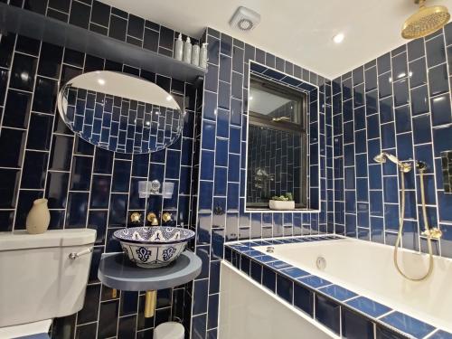 伦敦Jacuzzi Suite的蓝色瓷砖浴室设有浴缸和水槽