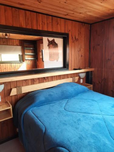埃尔基斯科PUNTA DE TRALCA SUITES的一间位于木制客房内的卧室,配有一张蓝色的床