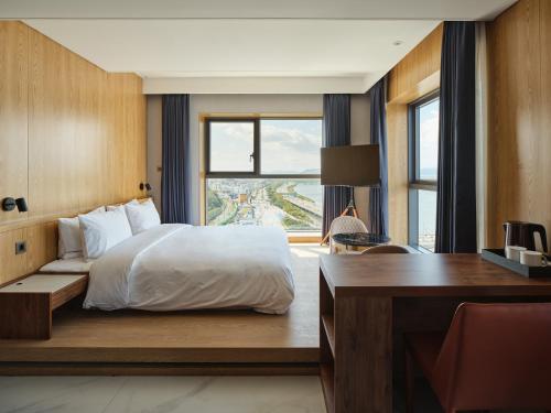 釜山Hotel tt Gupo的一间卧室配有一张床、一张书桌和一个窗户。