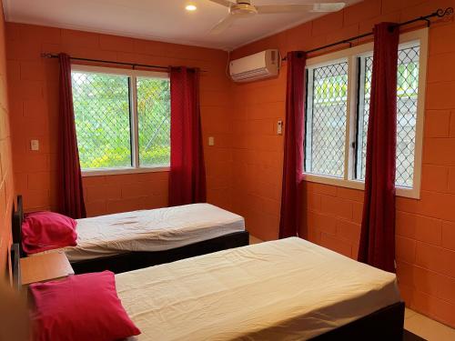 VaiteleKeris Rental Houses的宿舍间的两张床,设有红色的墙壁和窗户