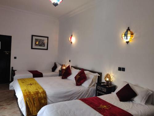 马拉喀什Riad Dar Foundouk and Spa的酒店客房设有三张床,墙上有灯