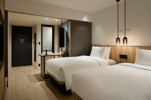 津山市Fairfield by Marriott Okayama Tsuyama的配有白色床单的酒店客房内的两张床