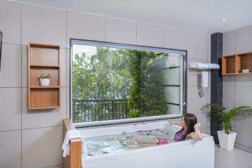 蒙纳Sprise Munnar Resort and Spa的坐在浴缸里的小女孩,有窗子